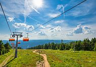 Wandern rund um Oberwiesenthal, Seilbahn über grüner Landschaft in Oberwiesenthal unter blauem Himmel.