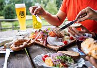 Gemütliche Brotzeit mit Bier und Wurst in alpiner Umgebung.