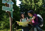 Junge Menschen an einer Kreuzung beim Wandern mit Landkarte