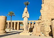 Antike Statue und Säulen im Karnak-Tempel bei strahlendem Sonnenschein.