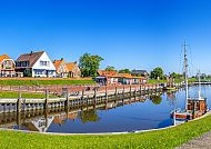Altstadt von Greetsiel, Idyllische Altstadt von Greetsiel mit Hafen und blauem Himmel., Greetsieler Altstadt mit Hafen und traditionellen Häusern.