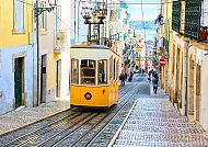 Lissabon, Gelbe Straßenbahn in Lissabons malerischer Altstadt., Gelbe Straßenbahn in Lissabon auf malerischer Kopfsteinpflasterstraße.