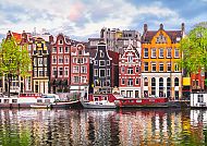 Bunte Grachtenhäuser in Amsterdam spiegeln sich im Wasser.