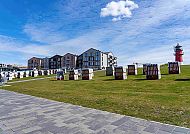 Büsum-Deich-Leuchtturm, Strandkörbe und Leuchtturm am Deich in Büsum bei blauem Himmel., Büsum-Deich mit Leuchtturm und Strandkörben unter blauem Himmel.