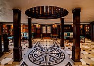 Elegante Lobby mit Marmorboden, Holzsäulen und warmer Atmosphäre.