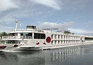 Flusskreuzfahrtschiff auf ruhigem Wasser bei sonnigem Wetter.