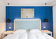 Hotel Zur alten Post, Zimmerbeispiel, Modernes Hotelzimmer mit blauer Wand und stilvollen Lampen.