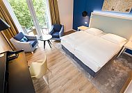 Zimmerbeispiel Wohnzimmer mit Balkon, Modernes Hotelzimmer mit Balkon und stilvollem Interieur.